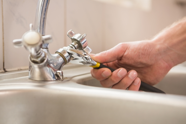 repairing faucet using wrench
